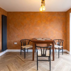 Dining room with orange feature wall and herringbone floor β renovations by Fen Developments