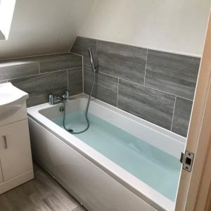 Bath with grey wall tiles under sloping ceiling β bathrooms by Fen Developments